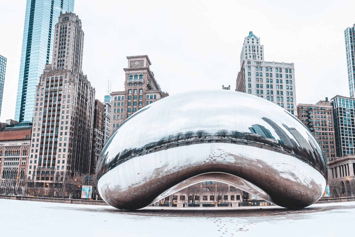 Cloud Gate in Chicago, Illinois, surrounded by snow-covered Millennium Park and downtown high-rise buildings.
