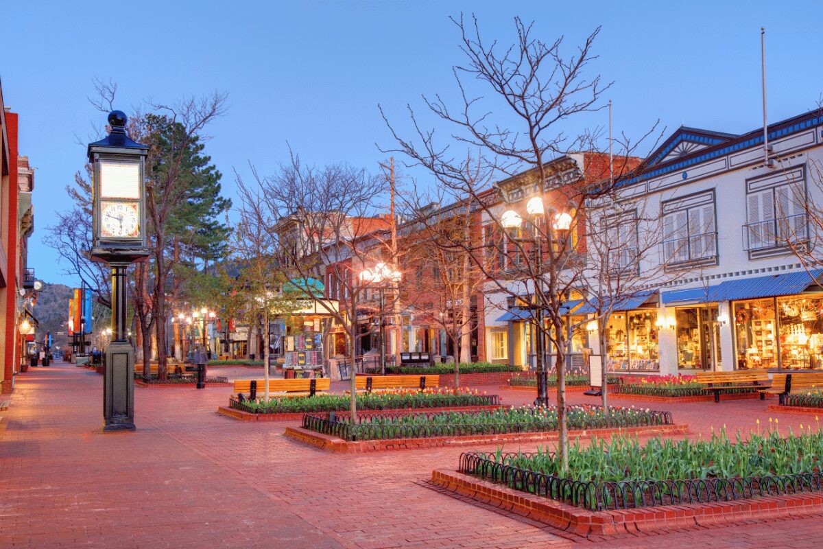 Downtown Boulder, Colorado, shopping district with retail storefronts, brick walkways and illuminated streetlights.