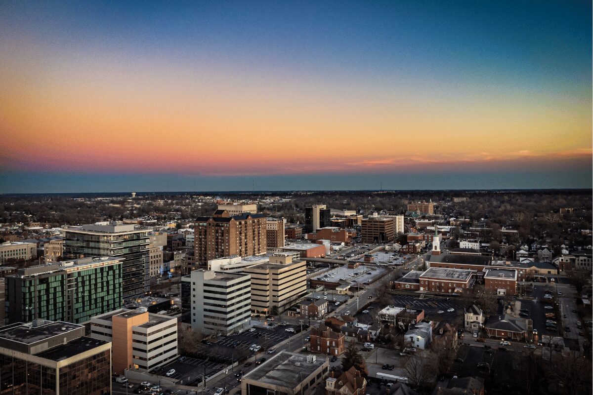 Aerial view of Lexington, Kentucky, at dusk with downtown office buildings, commercial rooftops and surrounding neighborhoods.