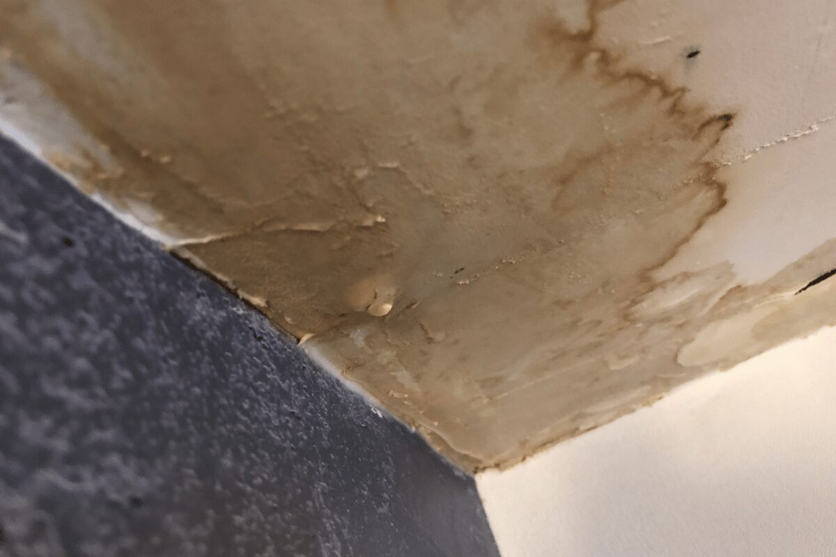 Interior ceiling water damage with brown staining, bubbling paint and peeling surface finishes.